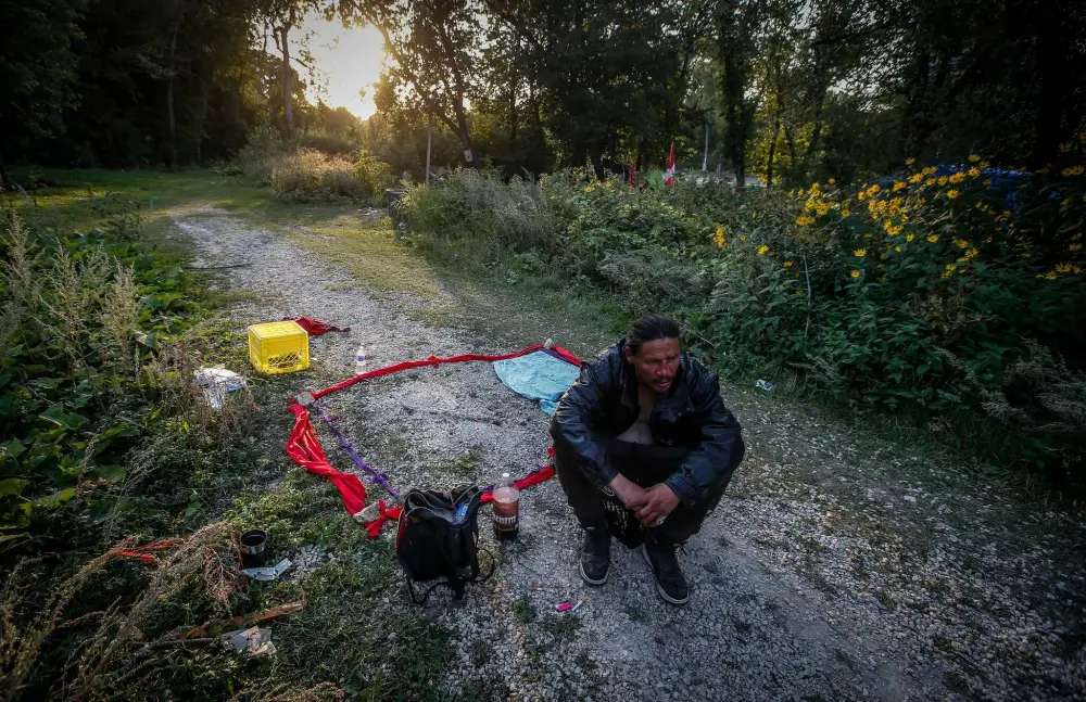 Andrew Desjarlais, a friend of Tammy Bateman, crouches next to a memorial for her in the park.